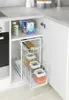 A white wire pull-out drawer organizer filled with various food items like pasta, grains, and spices, placed inside a kitchen cabinet. Anteprima dell’immagine prodotto