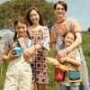 Four children are posing for a photo in an outdoor setting, possibly a field or park. Produktbild-Vorschau