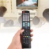 A hand holding a remote control in front of a blurred background of a family watching TV. Náhľad obrázku produktu