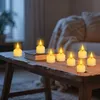 Several LED tealights are arranged on a wooden table in a dimly lit room, with a couch in the background. Produktbild-Vorschau