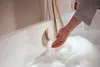 A hand is checking the temperature of the water in a bathtub filled with bubbles. Produktbild-Vorschau