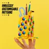 A hand holding a yellow LEGO DOTS pencil holder decorated with colorful patterns, with pencils and a ruler inside, against a yellow background. Podgląd zdjęcia produktu