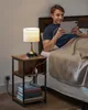 A man is sitting in bed using a tablet, next to a nightstand with a lamp and books. Náhled obrázku produktu