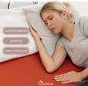 A woman sleeping on a bed with a red sheet and a striped pillow. Produktbild-Vorschau