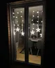 A window at night decorated with star-shaped string lights, with a dining room visible inside. Produktbild-Vorschau