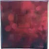 The image shows the front of a perfume box with a bokeh background. Produktbild-Vorschau