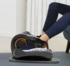 A person's legs and feet are shown using a compact elliptical machine under a desk. Podgląd zdjęcia produktu