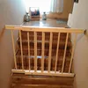 A wooden baby gate is installed at the top of a wooden staircase. Voir les images du produit