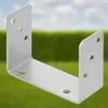 A silver U-shaped metal bracket is shown against a blurred background of green grass and a light blue sky. Podgląd zdjęcia produktu