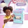 A young boy is smiling and holding the door of a toy oven. Podgląd zdjęcia produktu