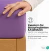 A hand is shown touching a purple fitted sheet on a wooden bed frame, with text overlays describing product features. Produktbild-Vorschau