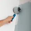 A hand is painting a wall with a paint roller. Voir les images du produit