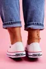 A close-up shot of a person's feet wearing white sneakers and blue jeans. Voir les images du produit