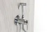 A close-up shot of a chrome bidet sprayer mounted on a light wood-grain textured wall. Podgląd zdjęcia produktu