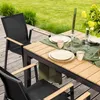 An outdoor dining set with chairs and a table, set up on a wooden deck with grass in the background. Produktbild-Vorschau