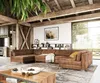 A spacious living room with a large sectional sofa, wooden beams, and a large window overlooking greenery.