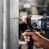 A person is using a Bosch drill to drill into a metal surface. Voir les images du produit