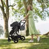 A woman pushing a stroller in a park. Produktbild-Vorschau