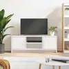A white TV stand with a television on top, placed in a room with a plant and a bookshelf. Anteprima dell’immagine prodotto