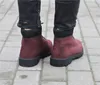 A person wearing dark jeans and burgundy Timberland boots standing on a paved walkway. Voir les images du produit