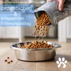 A hand pouring dog food into a stainless steel bowl. Produktbild-Vorschau