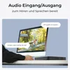 A computer monitor displaying a video feed of two children playing in a garden, with speech bubbles indicating a two-way audio conversation. A black NVR device is placed on a desk in front of the monitor. Produktbild-Vorschau