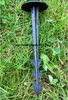 A black plastic landscape stake with multiple barbs is partially inserted into green grass. Náhľad obrázku produktu
