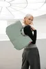 A woman is posing with a large tote bag over her shoulder in a modern, indoor setting with a circular ceiling light. Voir les images du produit