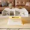 A modern white coffee table with integrated LED lighting and storage, placed in a living room setting with a brown leather sofa and a patterned rug. Produktbild-Vorschau