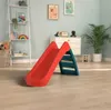A children's play area with a red and teal slide in the foreground, a white shelving unit on the left, and a white dresser on the right. Anteprima dell’immagine prodotto