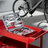 A bicycle tool kit is open on a red cart with a bicycle in the background. Produktbild-Vorschau