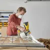 A man wearing a mask is painting a metal frame with a spray gun. Produktbild-Vorschau