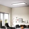 A modern living room with a sofa, armchair, window, and decorative items, featuring a large rectangular LED panel light on the ceiling. Produktbild-Vorschau