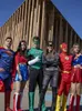 A group of people dressed as superheroes stand in front of a modern building. Produktbild-Vorschau