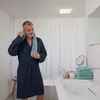 A man in a bathrobe drying his face with a towel in a bathroom. Produktbild-Vorschau