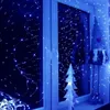 A window decorated with blue fairy lights, a Christmas tree, and a gnome. Náhled obrázku produktu