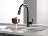 A black kitchen faucet with water running into a sink, with a bowl of potatoes in the background. Produktbild-Vorschau
