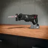 A black reciprocating saw with a battery pack attached is resting on a wooden surface in front of a concrete wall. Produktbild-Vorschau