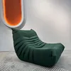 A green sofa is placed on a rug in front of a white wall with an illuminated orange oval shape on the wall. Voir les images du produit