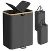 A black laundry basket with a wooden rim and a split lid is shown. Two smaller black laundry bags are placed to the right of the basket. Náhled obrázku produktu