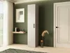 A tall, narrow cabinet is shown in a room with a green wall, a framed picture, a small shelf with books, and a door. Produktbild-Vorschau