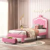 A pink upholstered bed with a crown-shaped headboard and LED lighting in a child's bedroom. Voir les images du produit