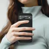 A person is holding a black smartphone case with a camera lens protector. Produktbild-Vorschau