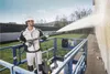 A man is using a pressure washer from a lift to clean a building exterior. Náhled obrázku produktu