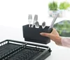 A hand is placing a cutlery holder filled with utensils onto a dish rack. Podgląd zdjęcia produktu