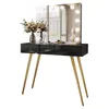 A black vanity table with gold legs and a lighted mirror, decorated with flowers and makeup. Produktbild-Vorschau