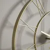 A close-up shot of a golden metal wall clock with Roman numerals. Voir les images du produit
