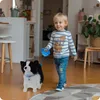 A young boy is walking indoors with a toy dog on a leash. Anteprima dell’immagine prodotto