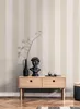 A modern interior scene featuring a wooden console table against a striped wallpaper, adorned with a bust, a vase with branches, and decorative spheres. Produktbild-Vorschau