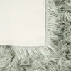 A close-up view of a fluffy rug with a white fabric backing. Produktbild-Vorschau
